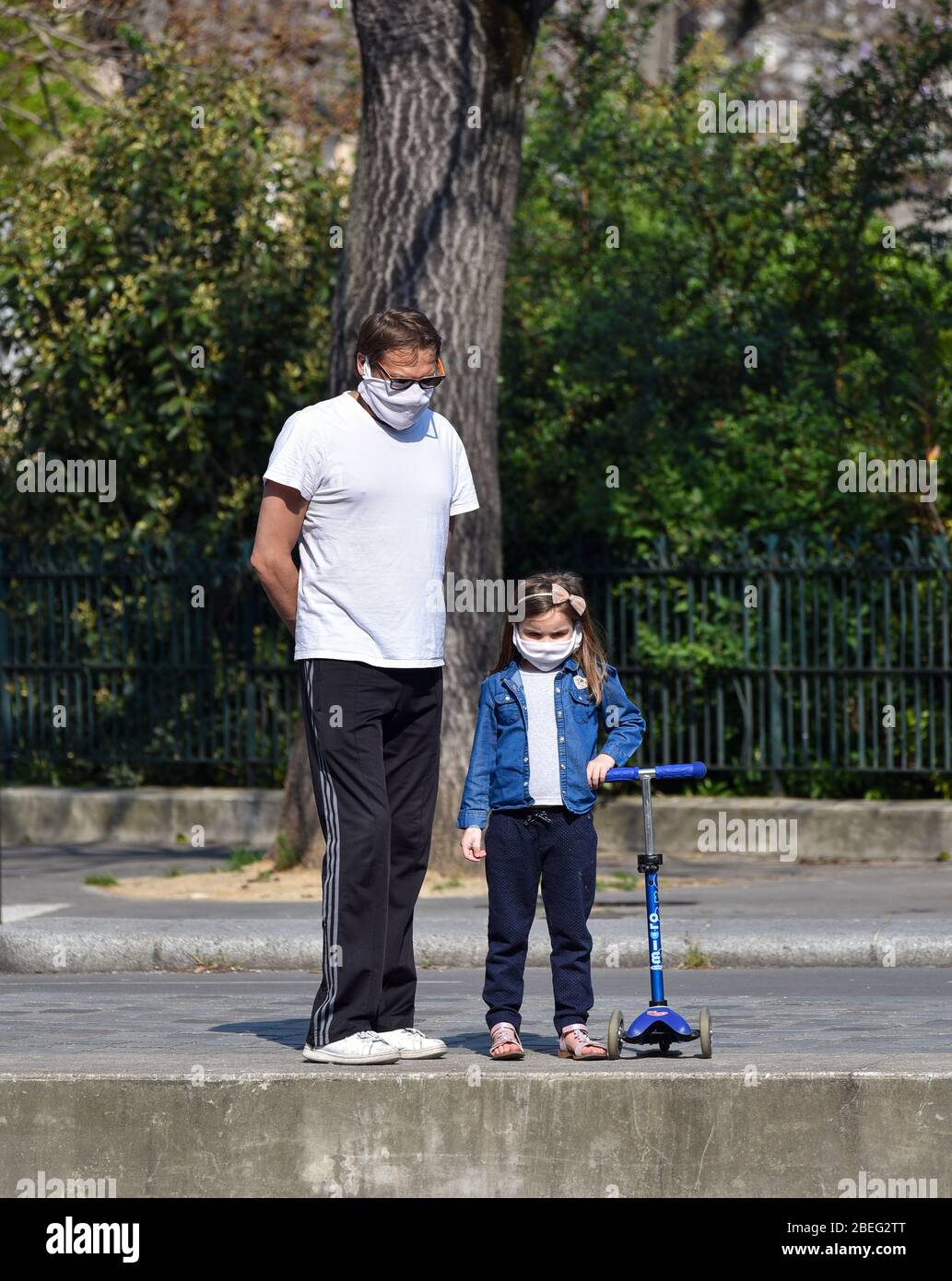 Un padre e sua figlia camminano per le strade di Parigi, indossando una maschera di stoffa fatta in casa durante la quarantena dichiarata in Francia. Foto Stock