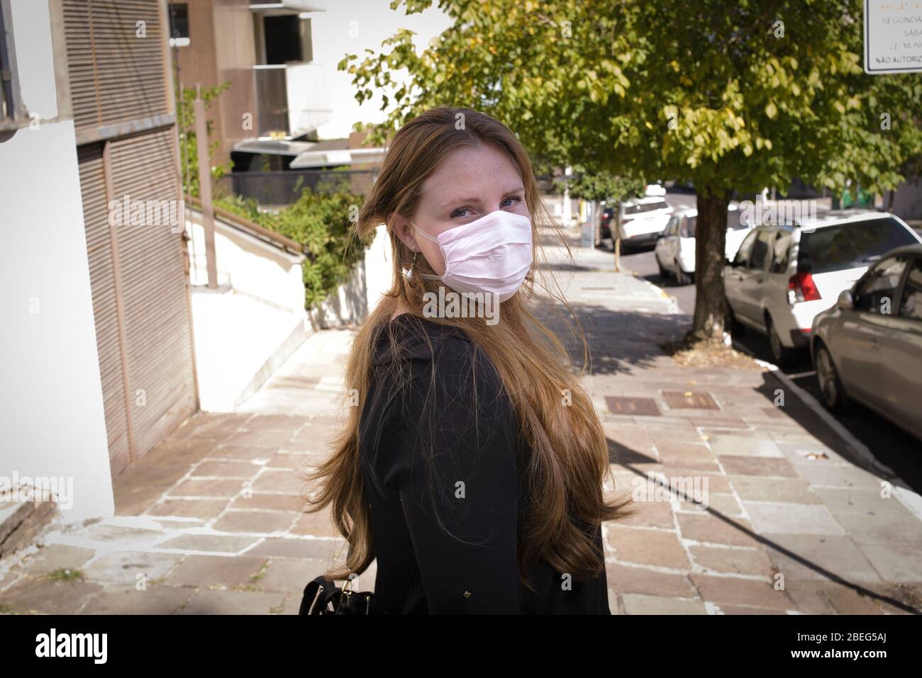 Donna con maschera durante la pandemia di coronavirus in Brasile. Come le regole per la facilità di blocco, più gente torna alle loro routine usuali. Foto Stock