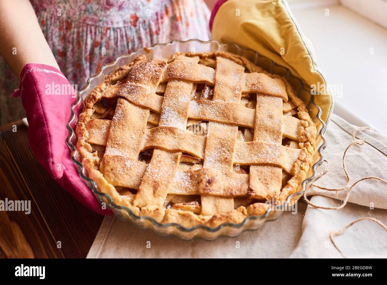 Messa a punto, disposizione o vita ferma con torta di mele fatta in casa sul tavolo coperto con tovaglia leggera in cucina a casa o studio Foto Stock