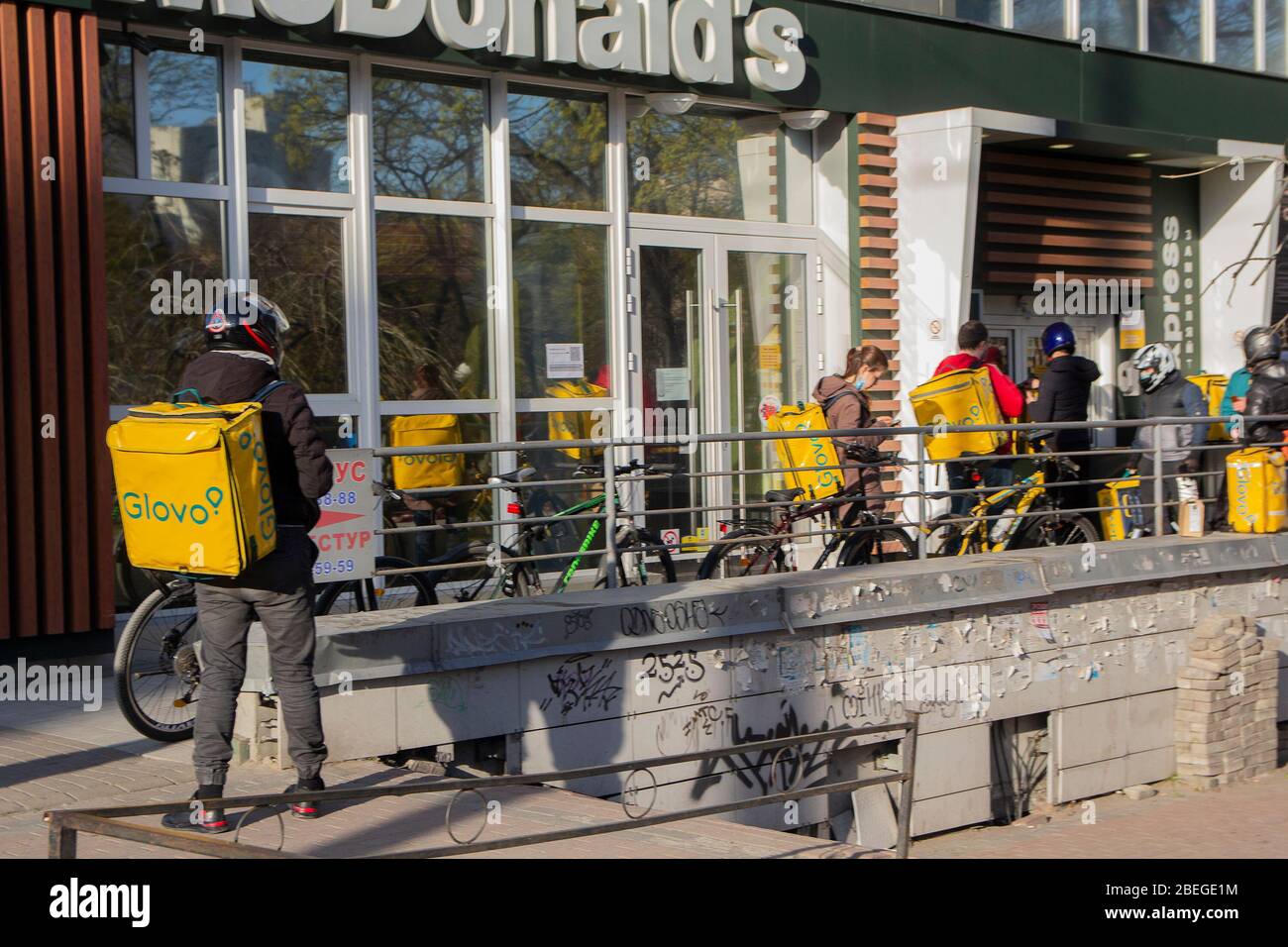 Kiev. Ucraina - 12 aprile 2020: Corrieri e servizi di consegna Glovo in coda vicino al McDonald's. L'Ucraina ferma bar, ristoranti e negozi ce Foto Stock