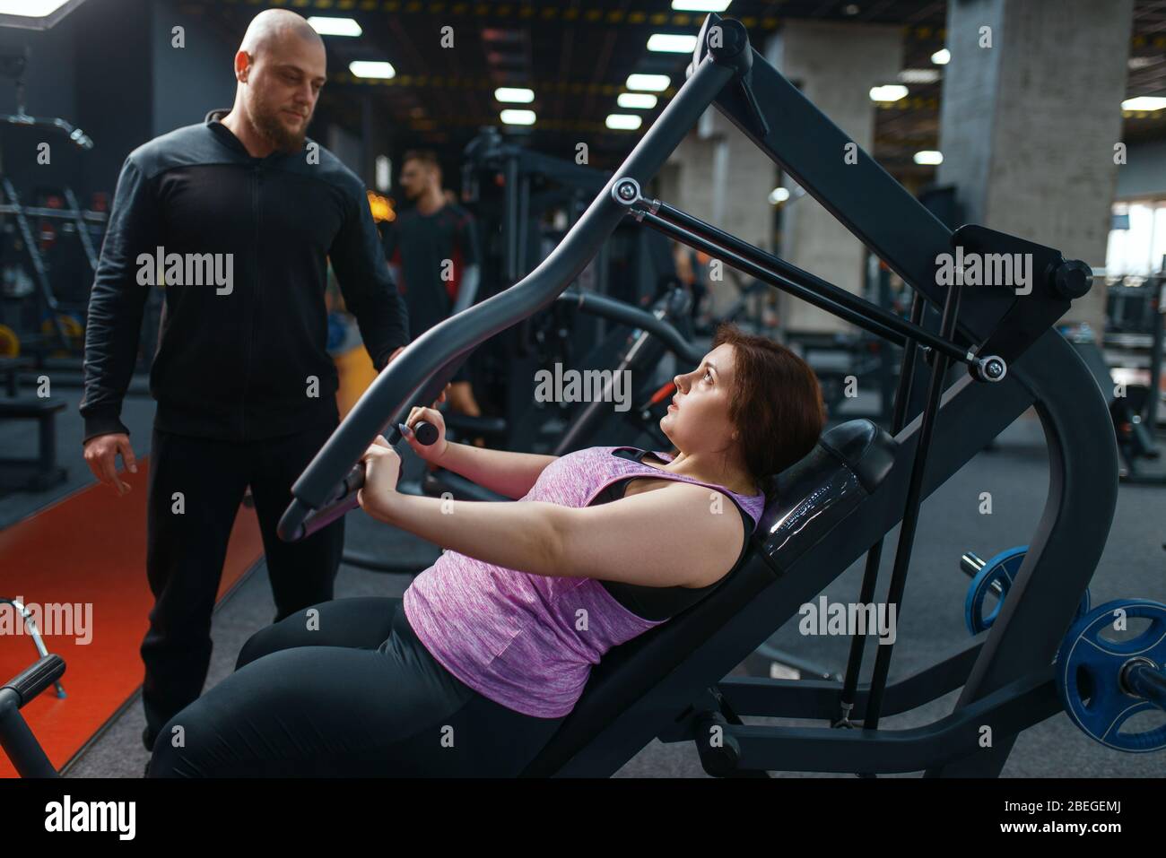 Donna in sovrappeso con allenatore che fa esercizio, palestra Foto Stock