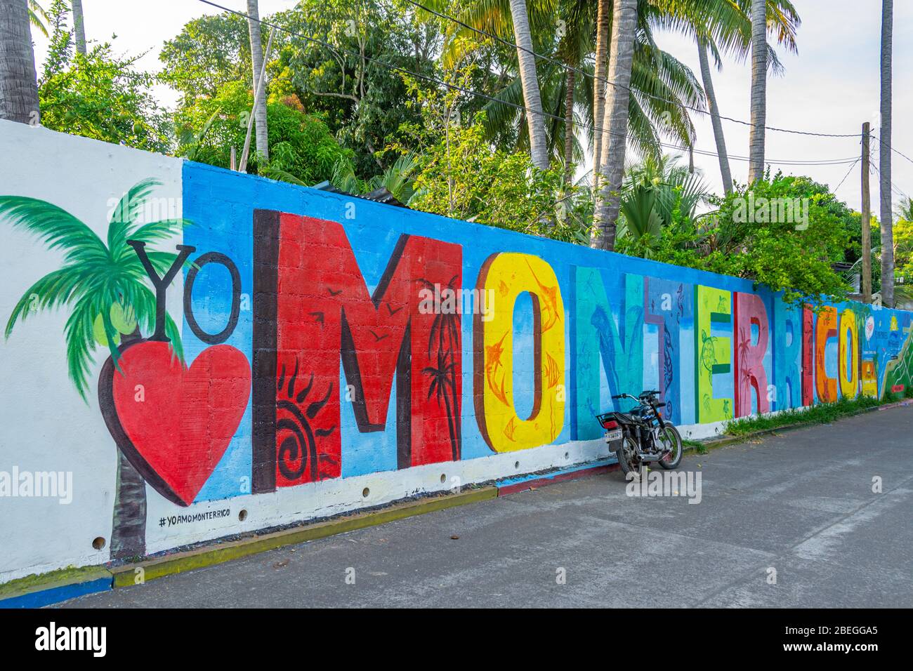 Lettere colorate che scrivono il nome di Monterrico dipinte sul muro dietro il molo dove gli arrivi arrivano in traghetto Foto Stock