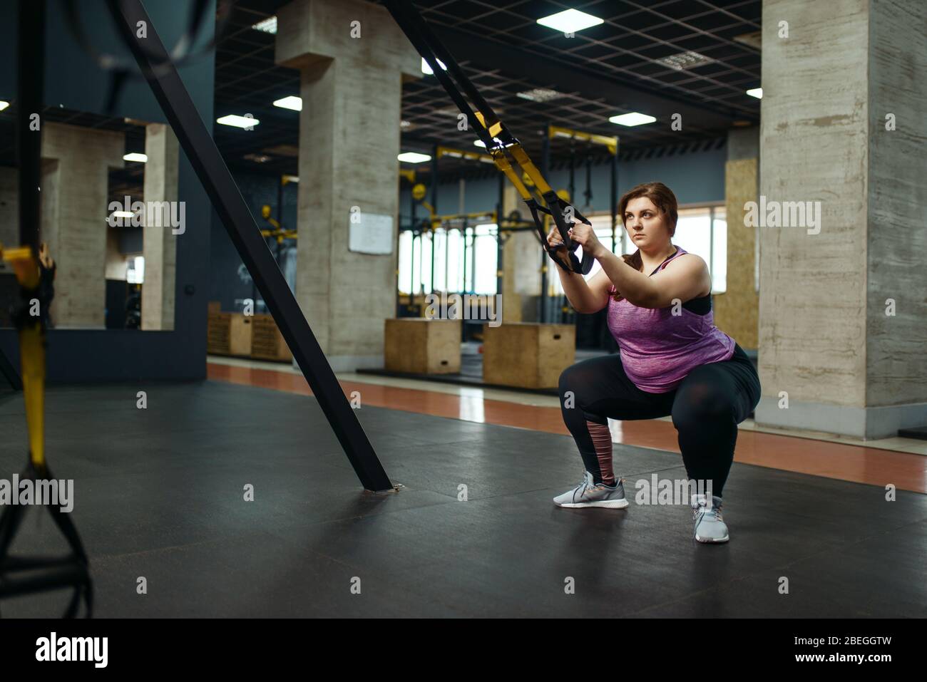 Donna in sovrappeso che fa esercizio di stretching in palestra Foto Stock