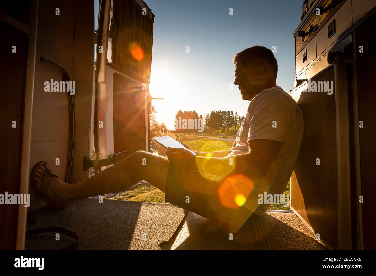 Ritratto di uomo incauta con tablet pc durante le vacanze campeggio nel suo furgone Foto Stock