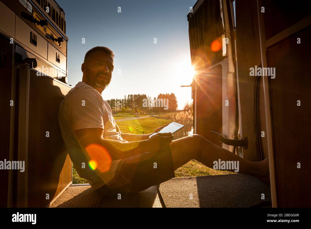Ritratto di uomo incauta con tablet pc durante le vacanze campeggio nel suo furgone Foto Stock