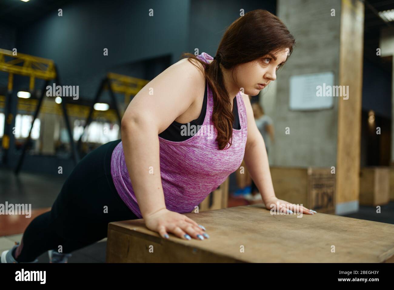 Donna in sovrappeso che fa esercizi di spinta in palestra Foto Stock