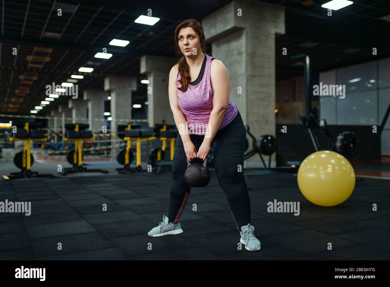 Donna sovrappeso, esercizio con kettlebell in palestra Foto Stock