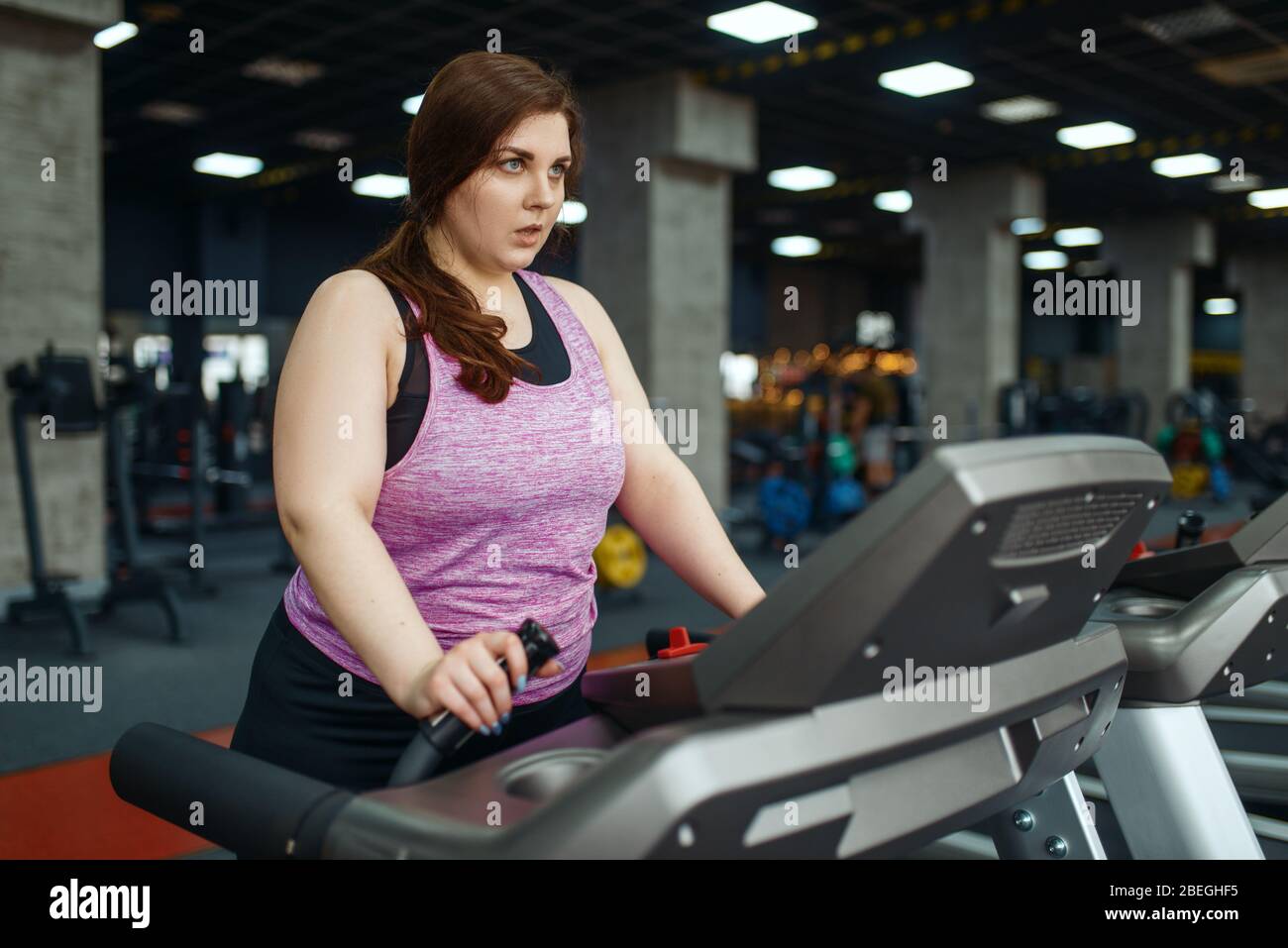 Donna in sovrappeso, esercizio su tapis roulant in palestra Foto Stock