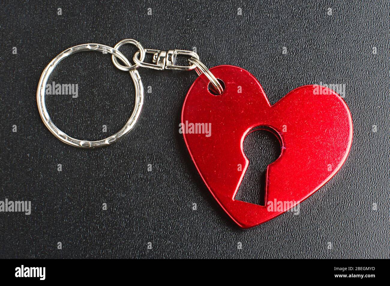 Portachiavi a forma di cuore rosso con foro per chiave isolato su sfondo nero Foto Stock