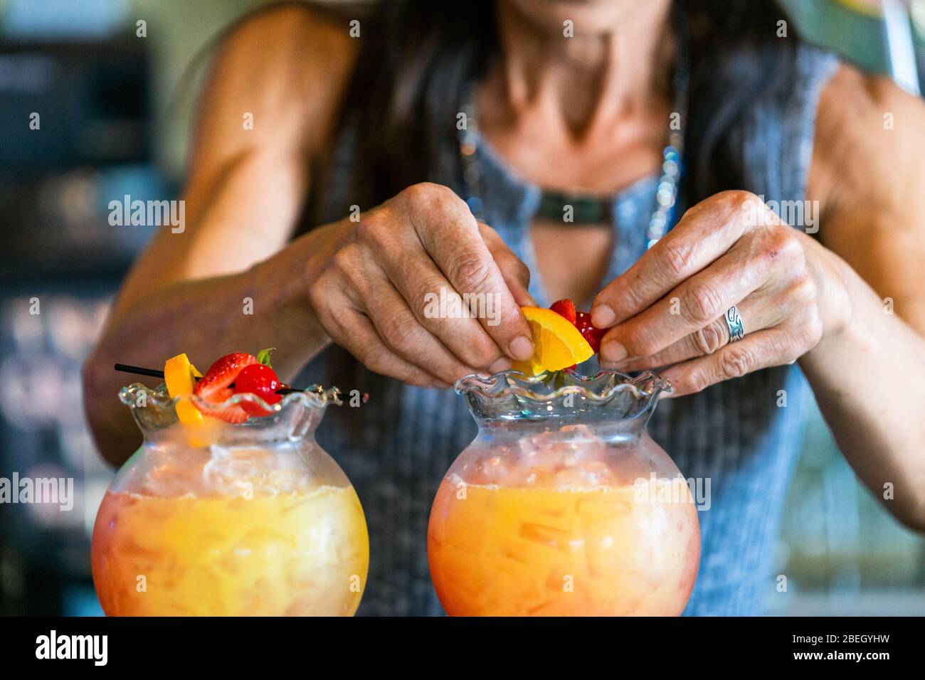 Primo piano delle mani della donna di mezza età che fanno bevande con frutta Foto Stock