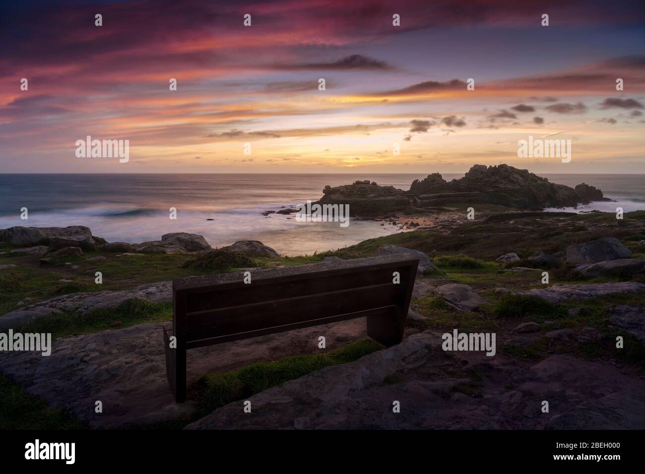 Panchina con splendida vista su alcune antiche rovine sulla costa Foto Stock