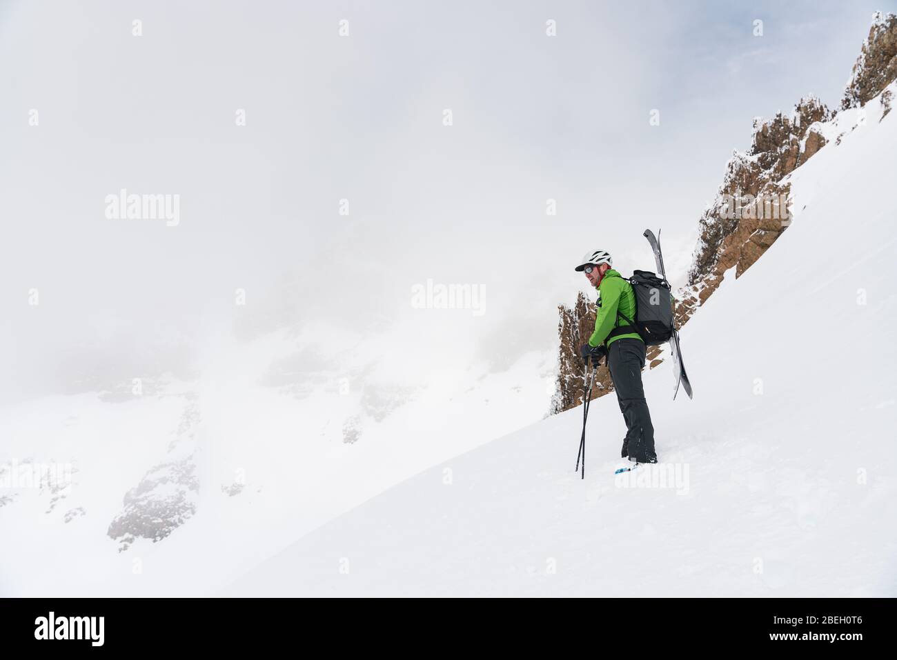Sciatore in piedi in cima alla linea che guarda fuori sulle montagne nebby Foto Stock