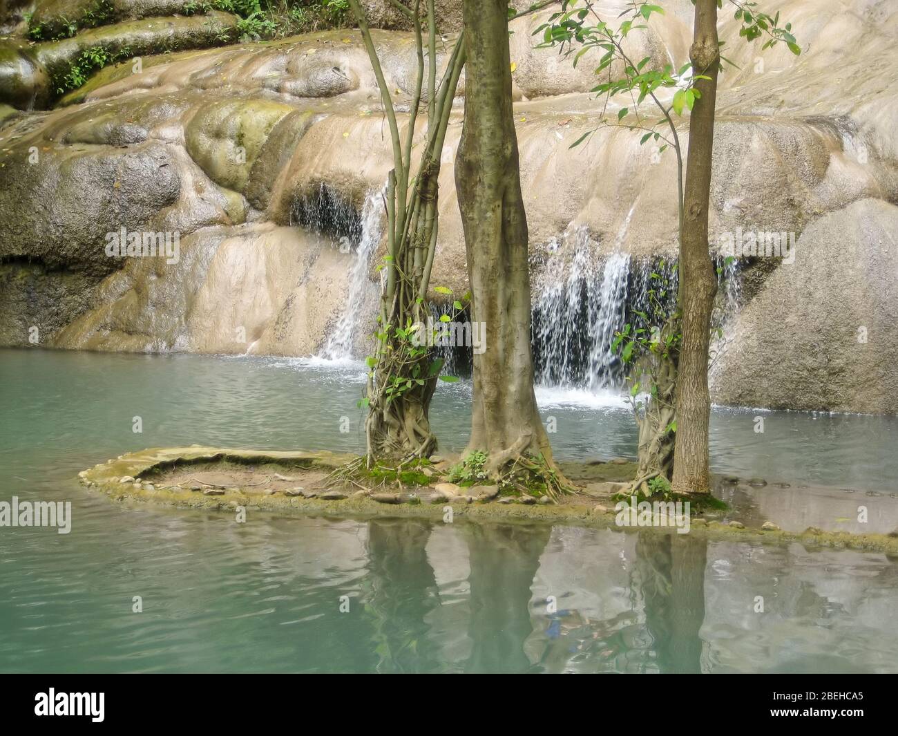 Piscina con una piccola cascata e alberi in un'area ricreativa progettata. Foto Stock