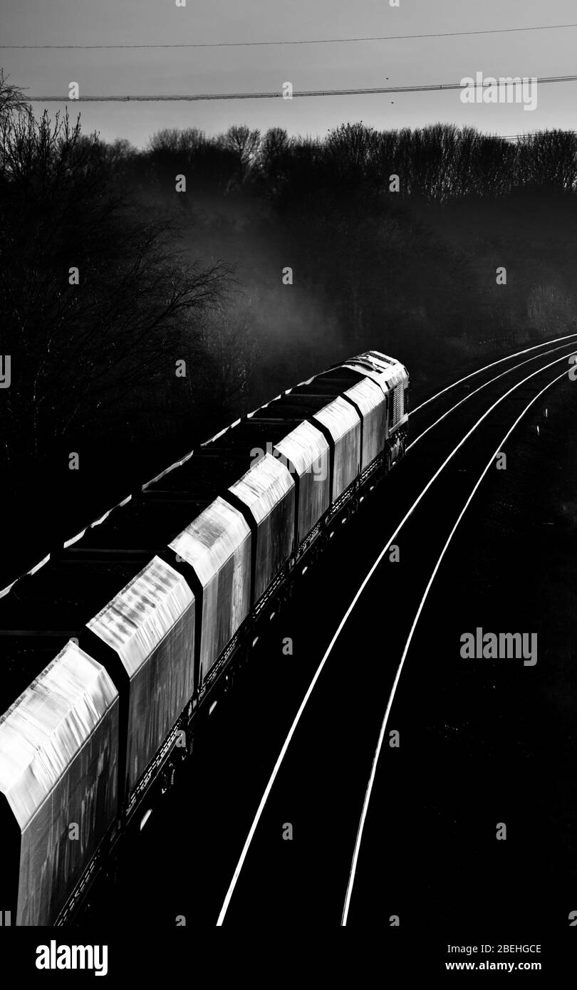 DB Cargo Rail UK Merry andare intorno al treno merci carbone in direzione del tramonto con carbone importato per una centrale elettrica Foto Stock