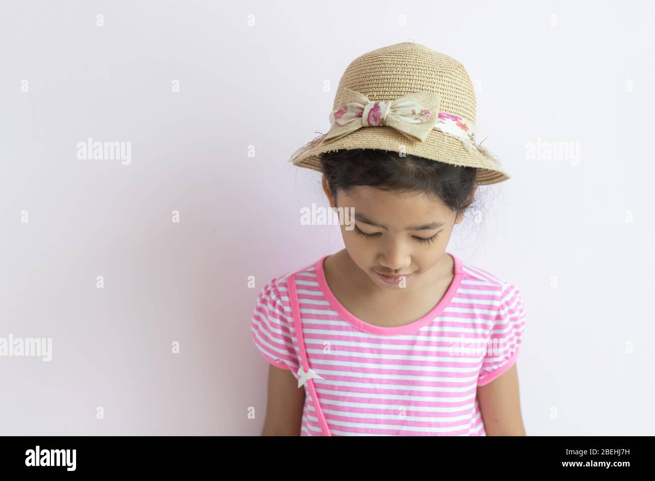 Ritratto dei bambini asiatici che indossano abiti a righe rosa e bianco la bambina indossa un cappello e guarda verso il basso. Foto Stock