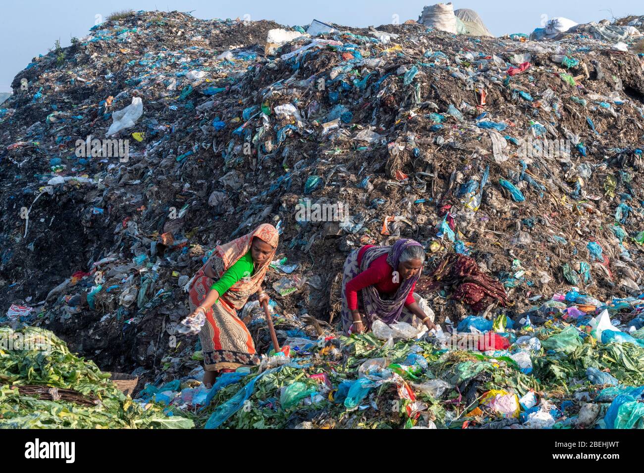 Due Donne con sacchi che smistano la spazzatura in un dump della spazzatura vicino Sylhet, Bangladesh Foto Stock