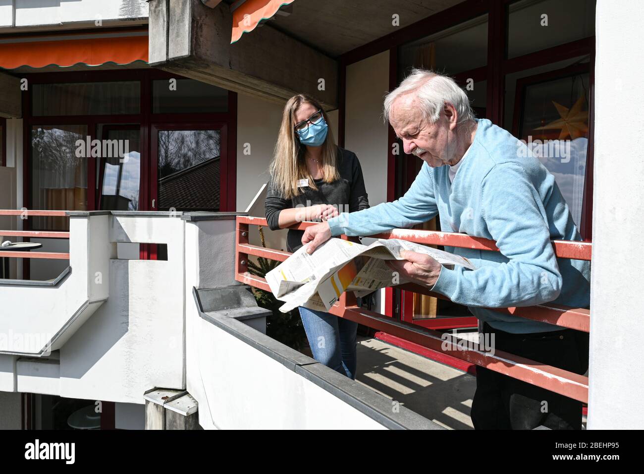 09 aprile 2020, Baden-Wuerttemberg, Leutkirch im Allgäu: Annabelle Emmermann, Vice responsabile dei servizi infermieristici, e residente Siegfried Jehmlich che chiacchiera sul balcone del cittadino anziano. Foto: Felix Kästle/dpa Foto Stock