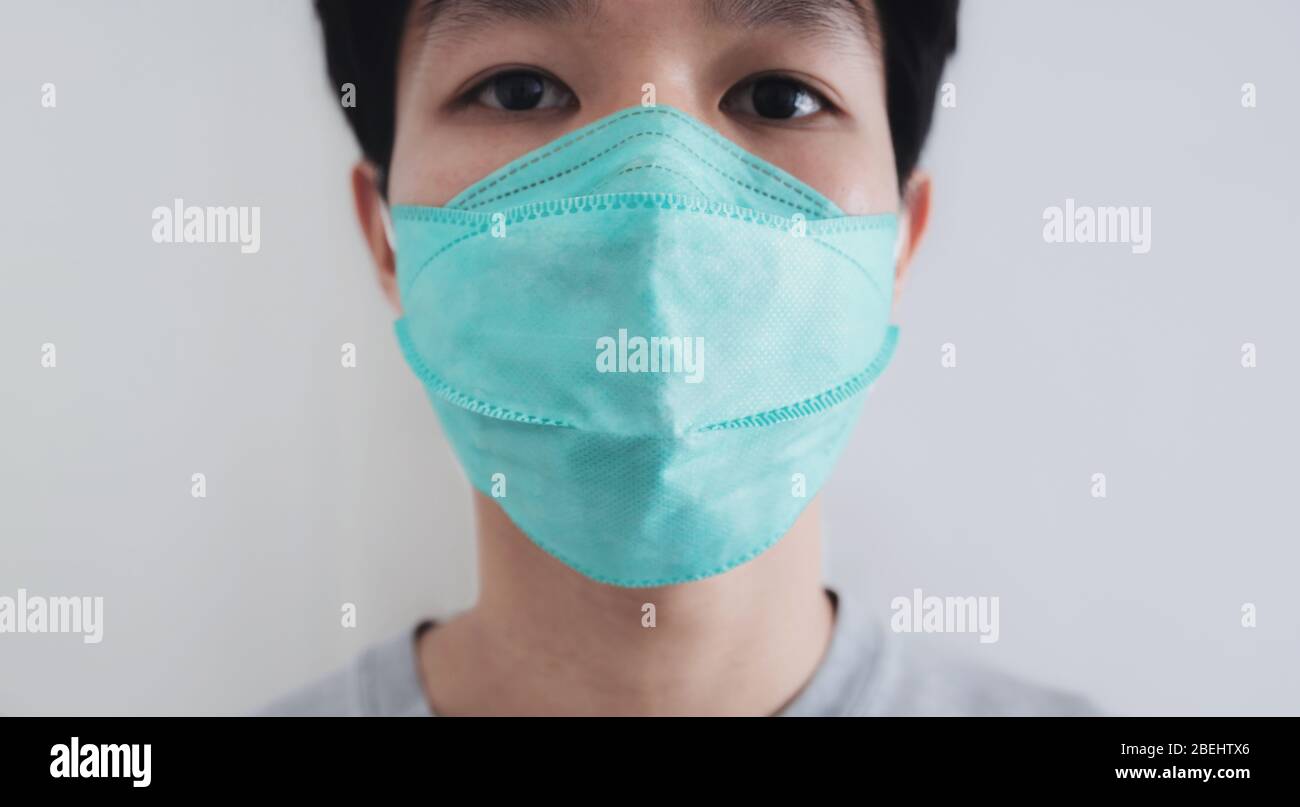 Primo piano un uomo che indossa una maschera protettiva per il viso. Prevenzione dal virus Corona, batteri e inquinamento atmosferico Foto Stock