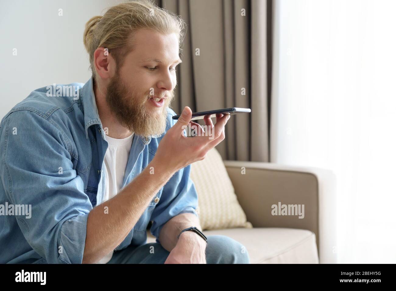 Giovane uomo che utilizza l'assistente vocale digitale virtuale sull'app per telefono cellulare. Foto Stock