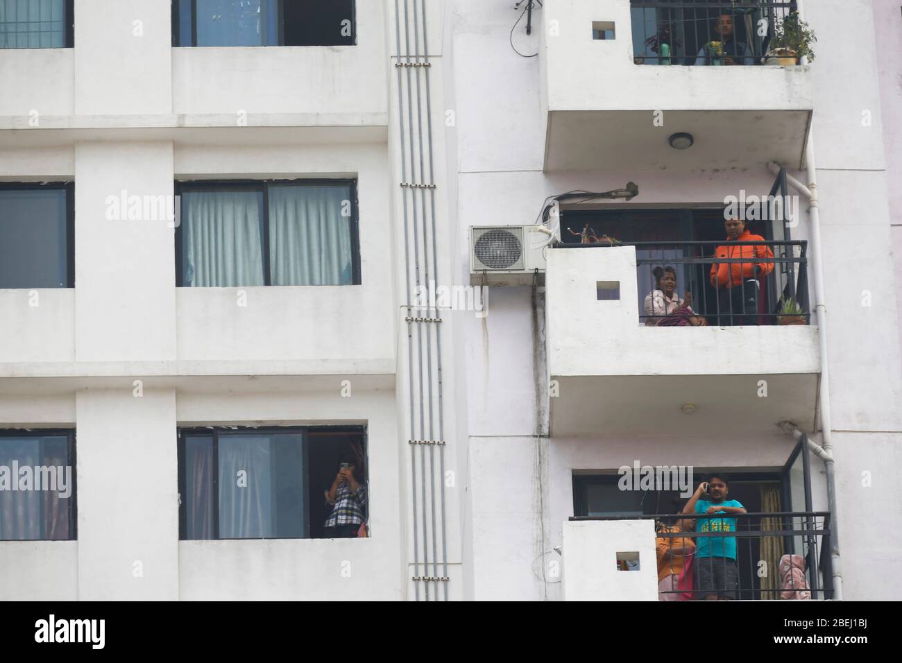 Bhaktapur, Nepal. 14 Aprile 2020. I residenti guardano fuori dalle loro finestre del balcone agli appartamenti di Sun City mentre il personale della polizia sigilla la zona dopo che tre membri di una famiglia che vi abitavano hanno provato positivo per la nuova malattia di coronavirus in test rapidi in Bhaktapur, Nepal, Martedì 14 aprile 2020. Credit: Skanda Gautam/ZUMA Wire/Alamy Live News Foto Stock