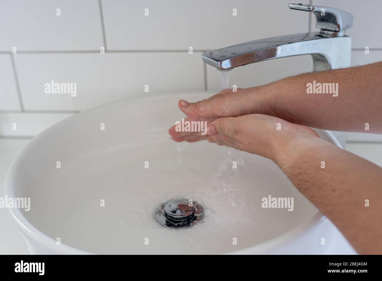 Ragazza lavando le mani sotto un rubinetto moderno e lavandino durante la pandemia 2020 covid-19 Foto Stock