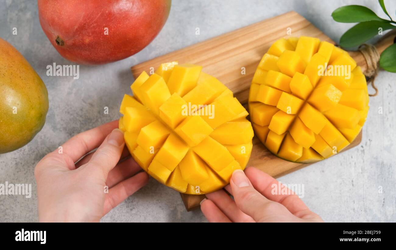 Fetta di mango perfetta tagliata a cubetti. Mani femminili che tengono fresco e succoso mango. Come tagliare il mango tutorial Foto Stock