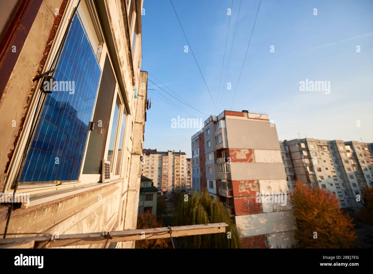 Pannello solare sul balcone di un edificio a più piani sullo sfondo di una zona residenziale della città con cielo blu chiaro in una giornata calda. Foto Stock