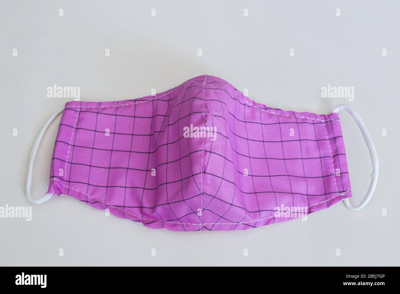 La maschera facciale in tessuto antipolvere aiuta le persone a evitare di ammalarsi. Colore rosa su sfondo bianco. Foto Stock