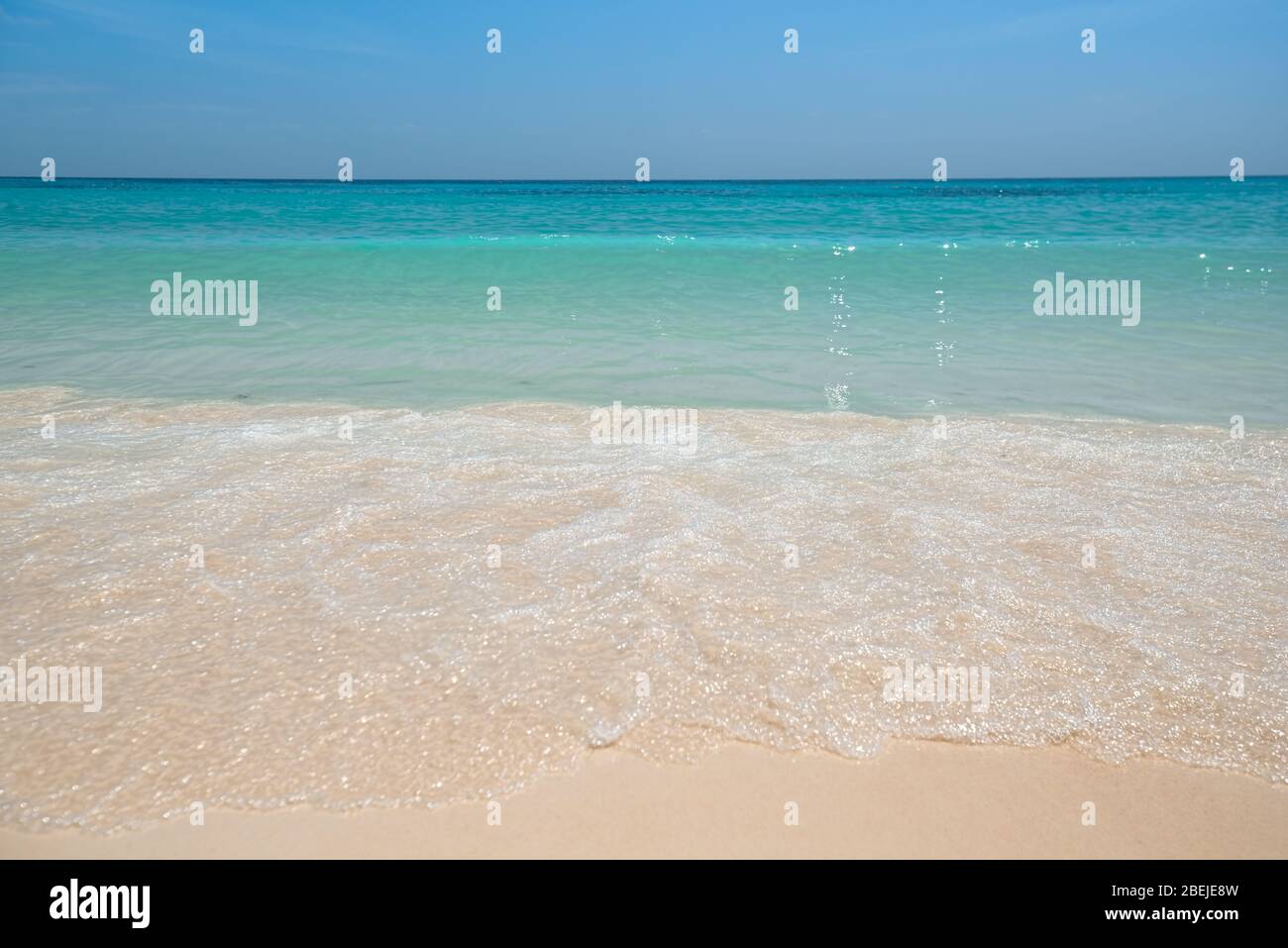 Mare tropicale con bella acqua acquamarina e onda di schiuma bianca che si rompe su spiaggia di sabbia fine giallo. Fondo marino. Thailandia Foto Stock