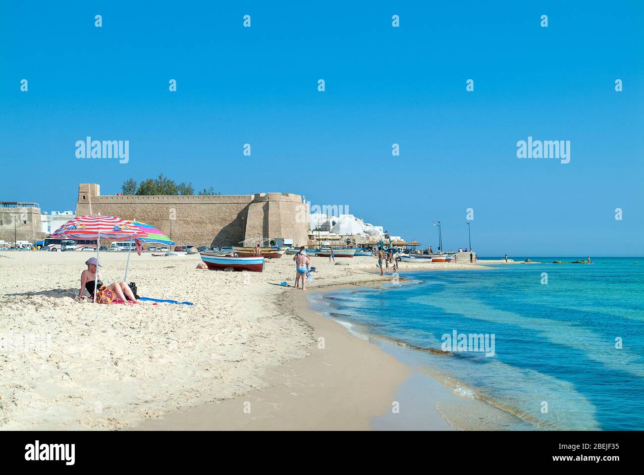 Prendere il sole sulla spiaggia di Ribat Town con barche da pesca, Hammamet, Tunisia Foto Stock