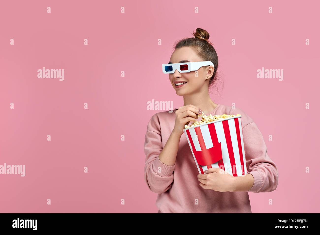 bella donna caucasica con occhiali 3d rosso-blu e mangiare popcorn dal  secchio mentre si guarda un film isolato su sfondo rosa. spazio copia Foto  stock - Alamy