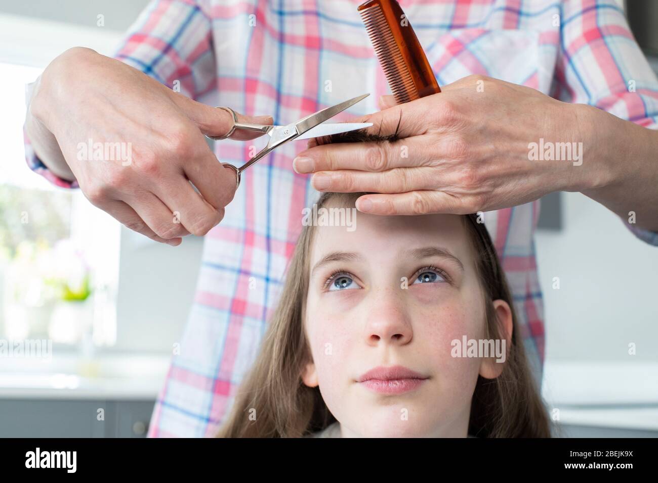 Madre che taglia i capelli preoccupati delle Figlie a casa durante il blocco Foto Stock