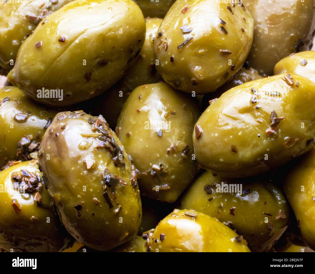 Olive verdi con erbe come sfondo. Mangiare sano. Cucina mediterranea. Disposizione piatta. Primo piano Foto Stock