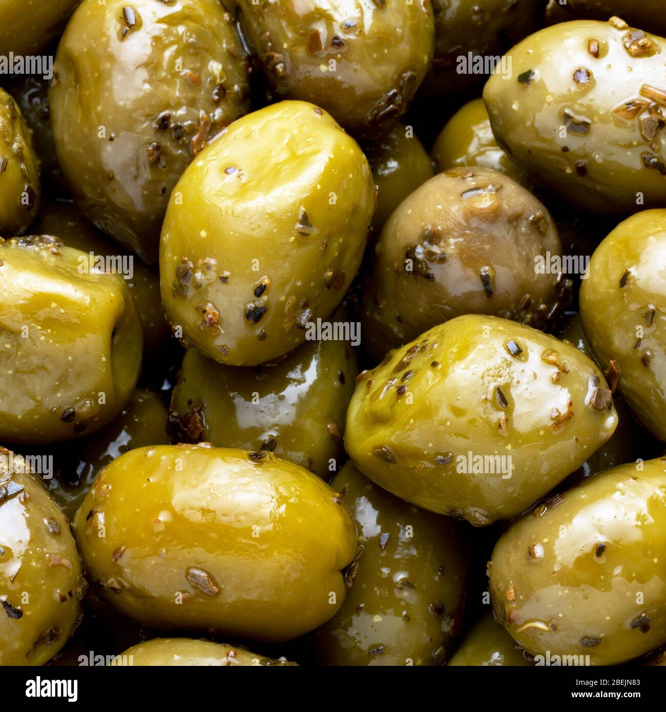 Olive verdi con erbe come sfondo. Mangiare sano. Cucina mediterranea. Disposizione piatta. Primo piano Foto Stock