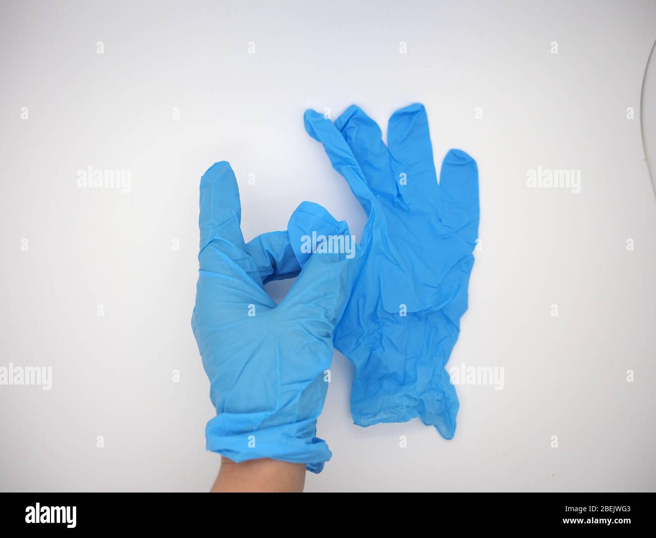 Mano che indossa UN guanto monouso blu (PPE) che si alza e raccoglie UN paio di occhiali di protezione, Londra, Regno Unito Foto Stock