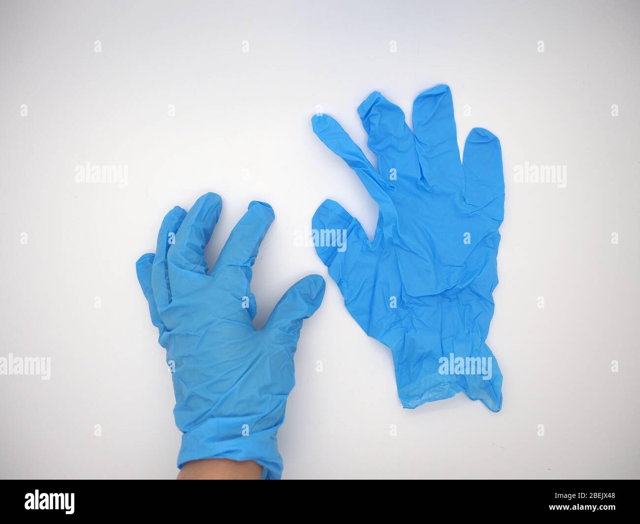Aprile 2020, mano che indossa UN guanto monouso blu che raccoglie un altro guanto monouso blu , Londra, Regno Unito Foto Stock