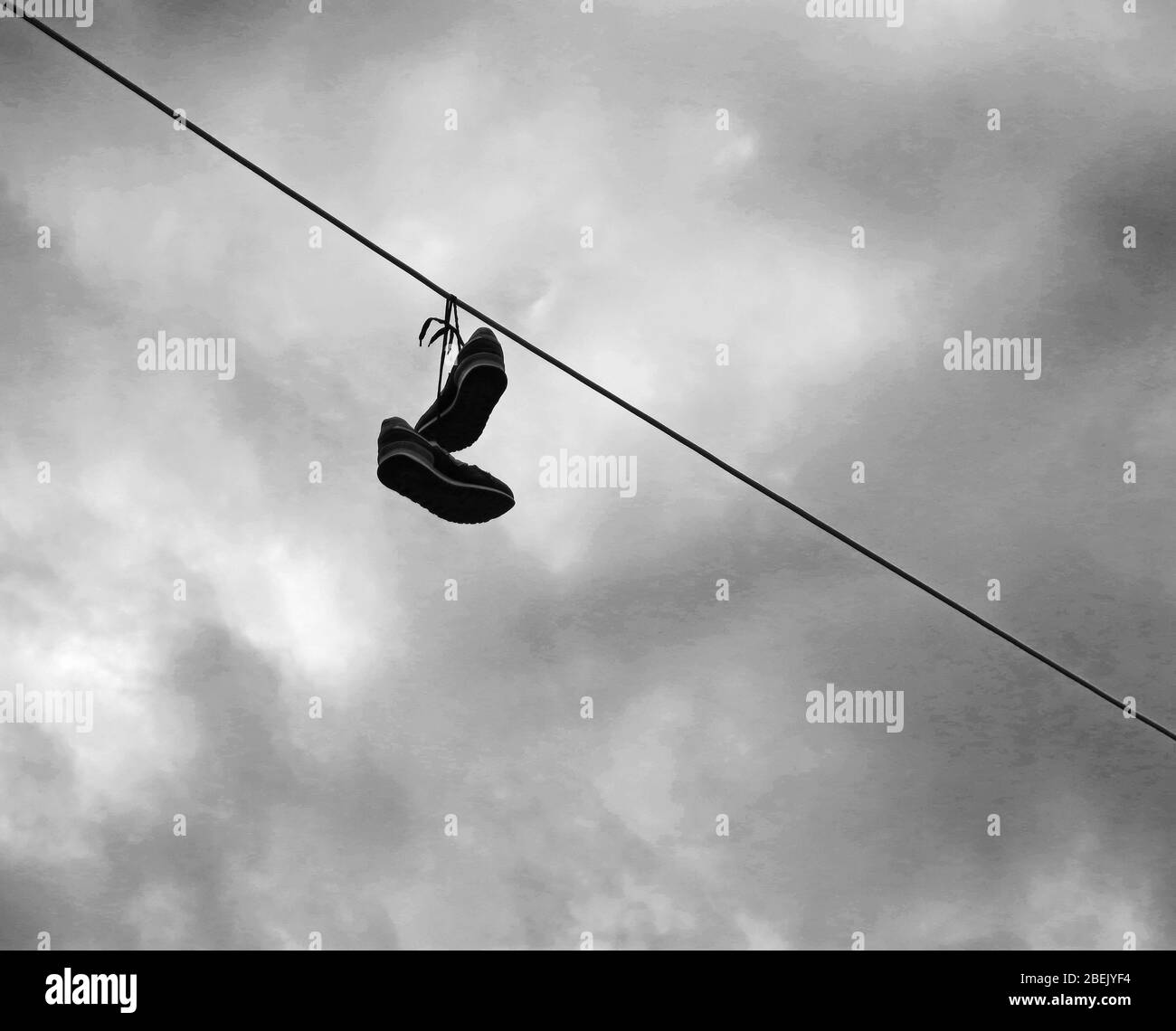 Coppia di scarpe legate insieme, gettate su una linea elettrica come un prank a qualcuno. Concetto: Minimalismo nella fotografia. Foto Stock