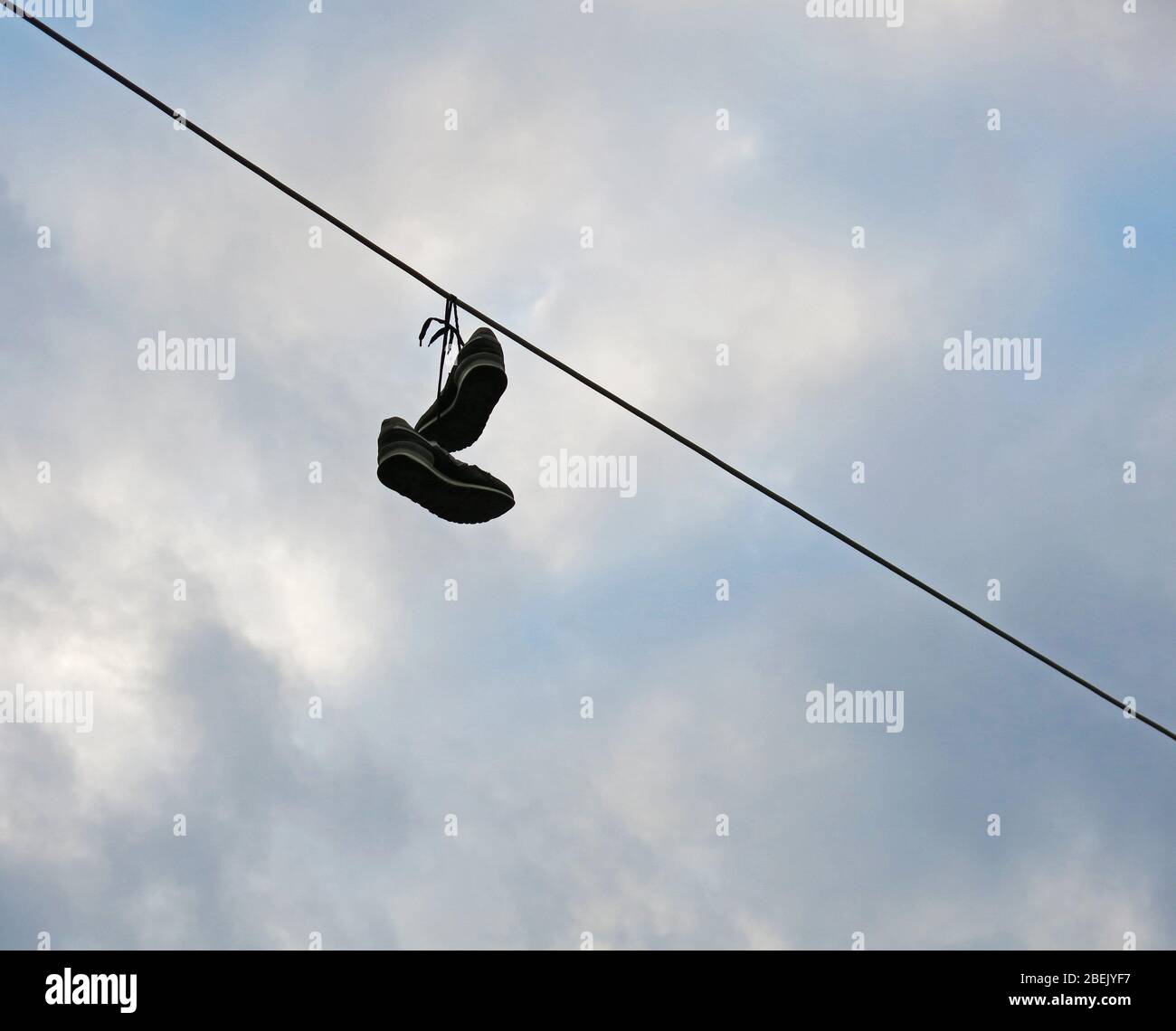 Coppia di scarpe legate insieme, gettate su una linea elettrica come un prank a qualcuno. Concetto: Minimalismo nella fotografia. Foto Stock