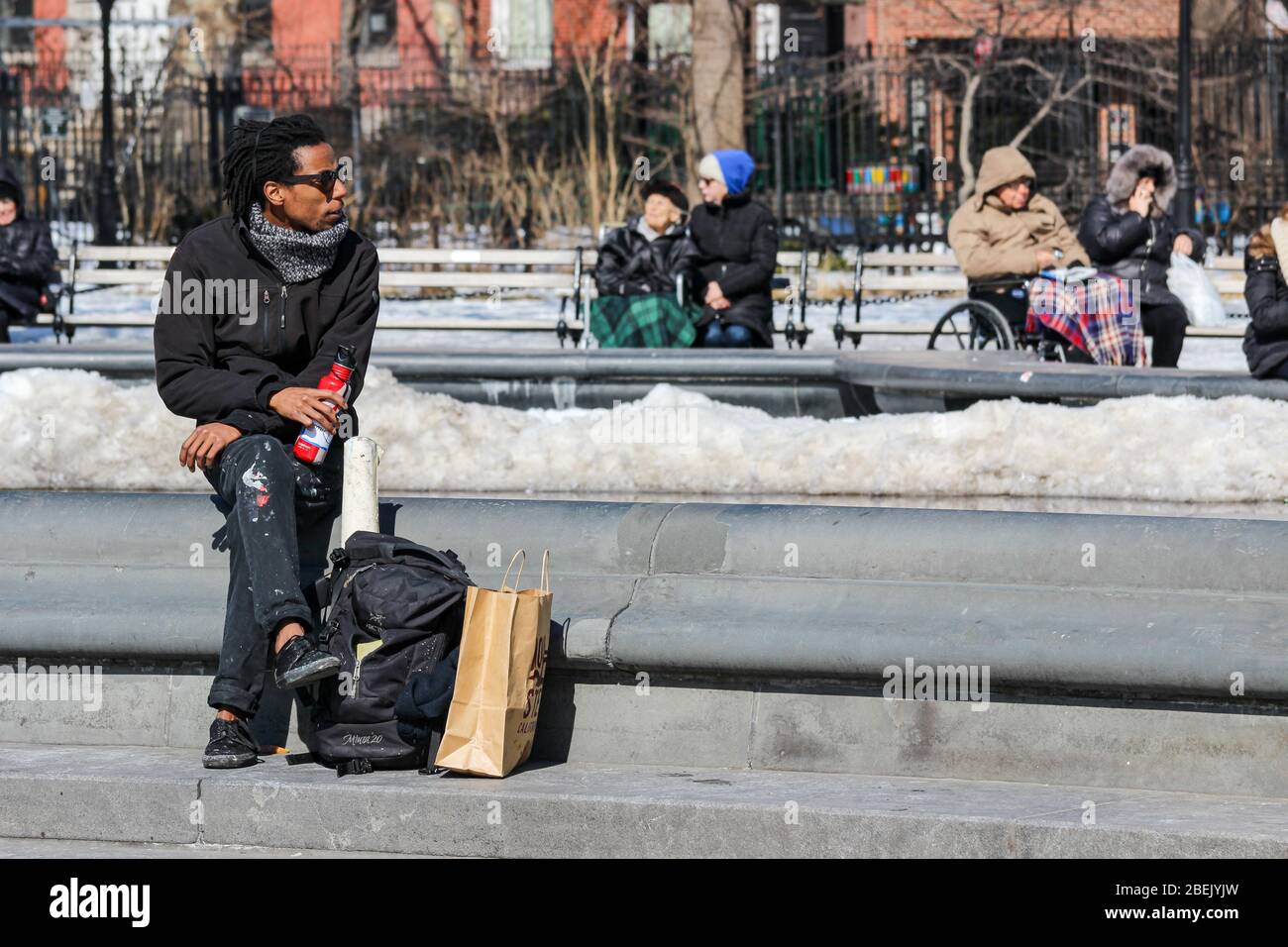 Uomo con macchie di vernice sui suoi pantaloni a fare una pausa pranzo a Washington Square Park a Manhattan, New York City, Stati Uniti d'America Foto Stock