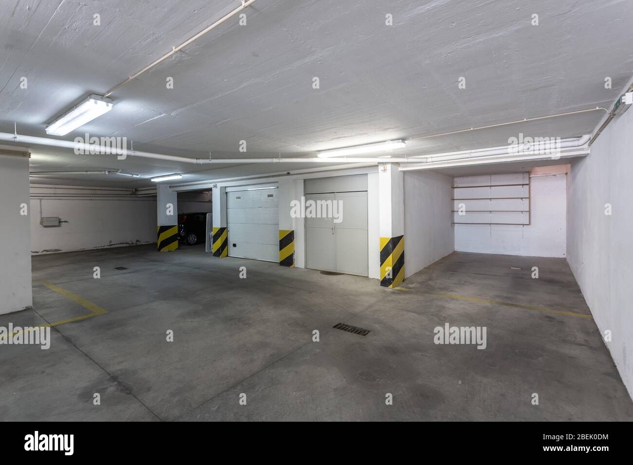 Garage comune per il parcheggio auto in un edificio a più piani con tubi fognari. Foto Stock