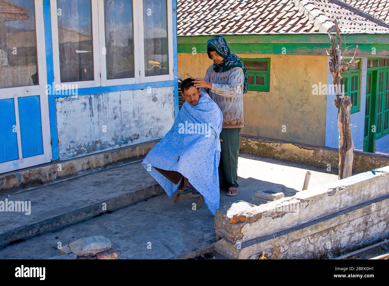 Uomo che ha un taglio di capelli in un piccolo villaggio tradizionale di Cemoro Lawang. Giava orientale, Indonesia. Foto Stock