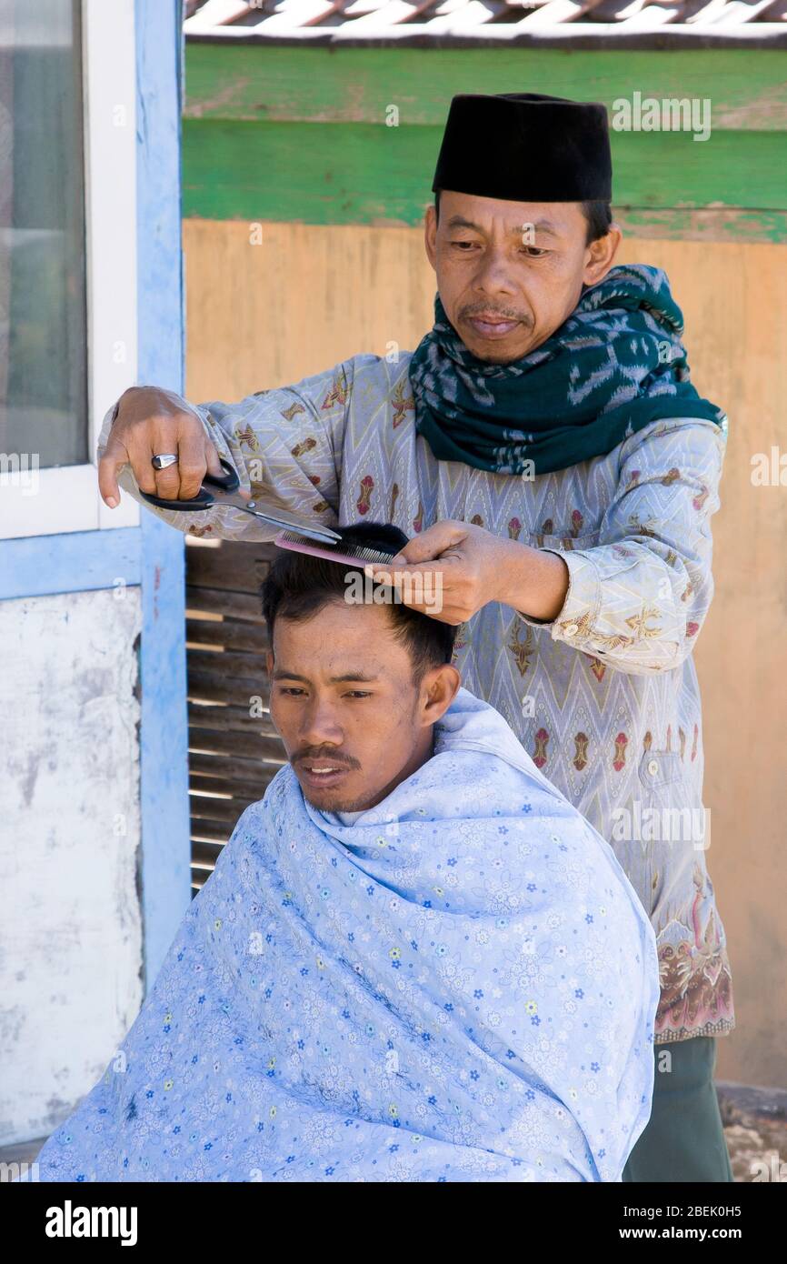 Uomo che ha un taglio di capelli in un piccolo villaggio tradizionale di Cemoro Lawang. Giava orientale, Indonesia. Foto Stock