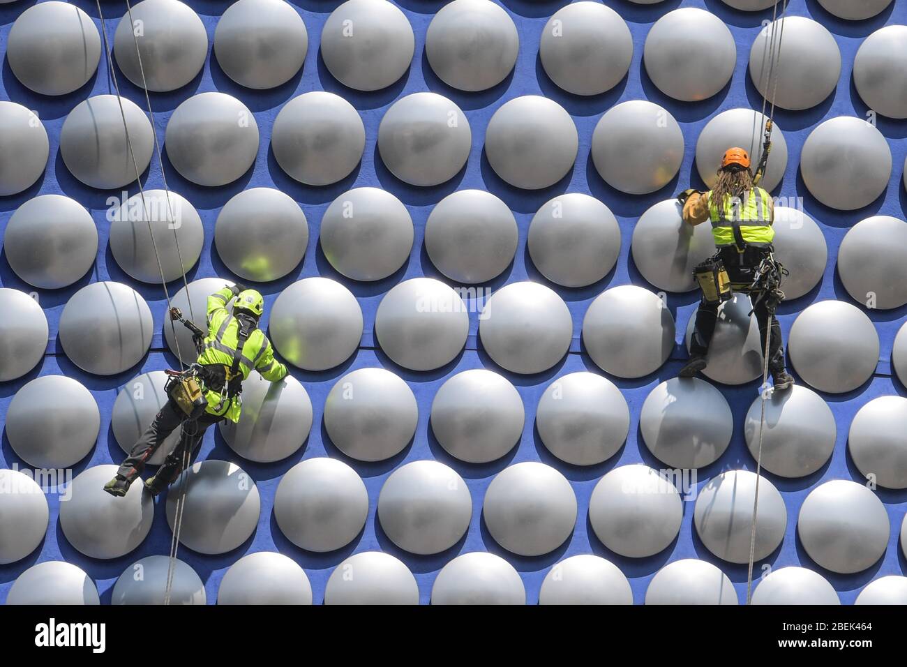 Birmingham, West Midlands, Regno Unito. 14 aprile 2020. Gli operai si scagliano lungo l'esterno del Selfridges nel centro di Birmingham per controllare se uno dei dischi è allentato. I lavoratori hanno utilizzato il blocco per lavorare senza causare gravi disagi ai pedoni sottostanti. Credito: Interrompi stampa Media/Alamy Live News Foto Stock