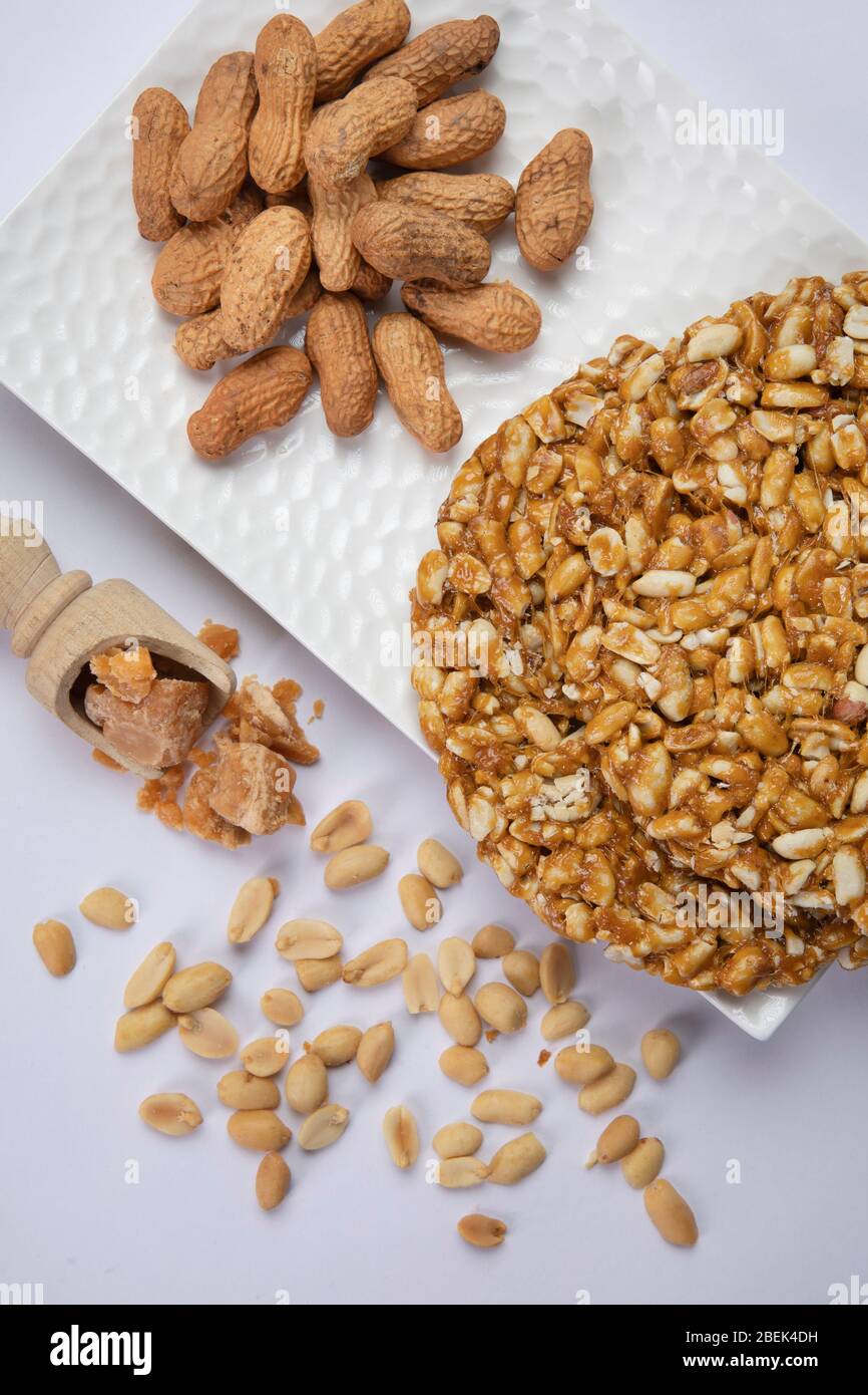 Arachidi e chikki tenuti su un vassoio bianco con jaggery e arachidi. Foto Stock