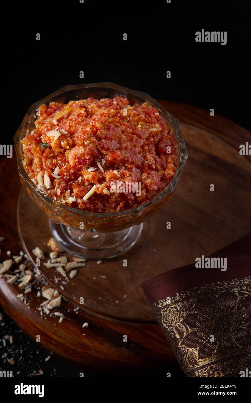Gajar ka halwa tenuto in una ciotola accanto ad un panno e pistacchi schiacciati. Foto Stock