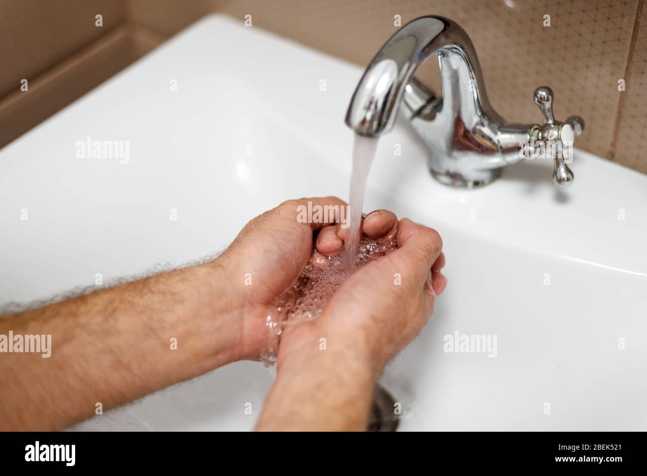 Lavaggio delle mani dell'uomo con acqua e sapone sotto la gru. Foto Stock