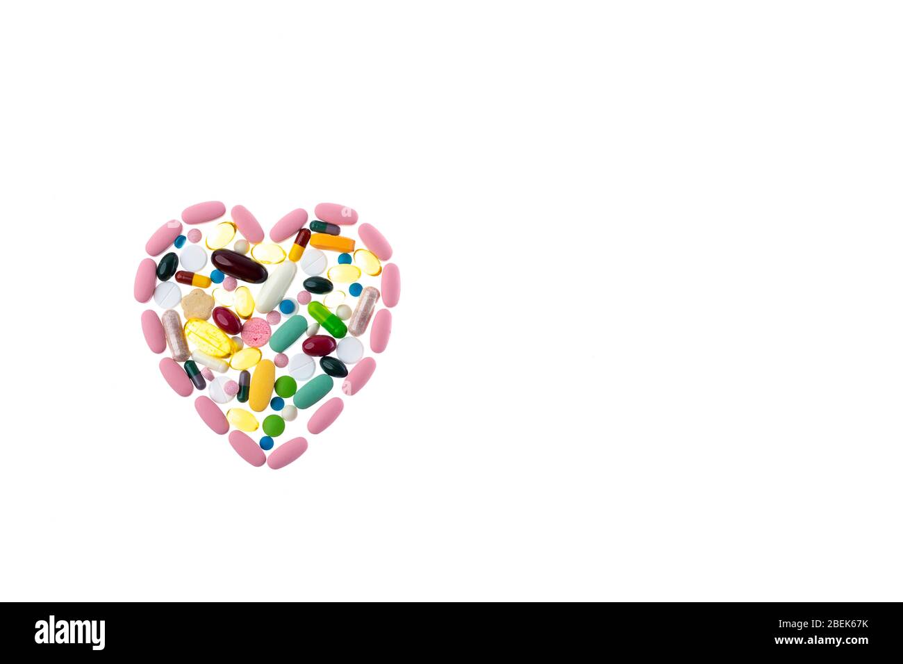 Pillole multicolore a forma di cuore su sfondo bianco isolato. Dose giornaliera di vitamine. Forma del cuore fatta di compresse, concetto di trattamento e. Foto Stock