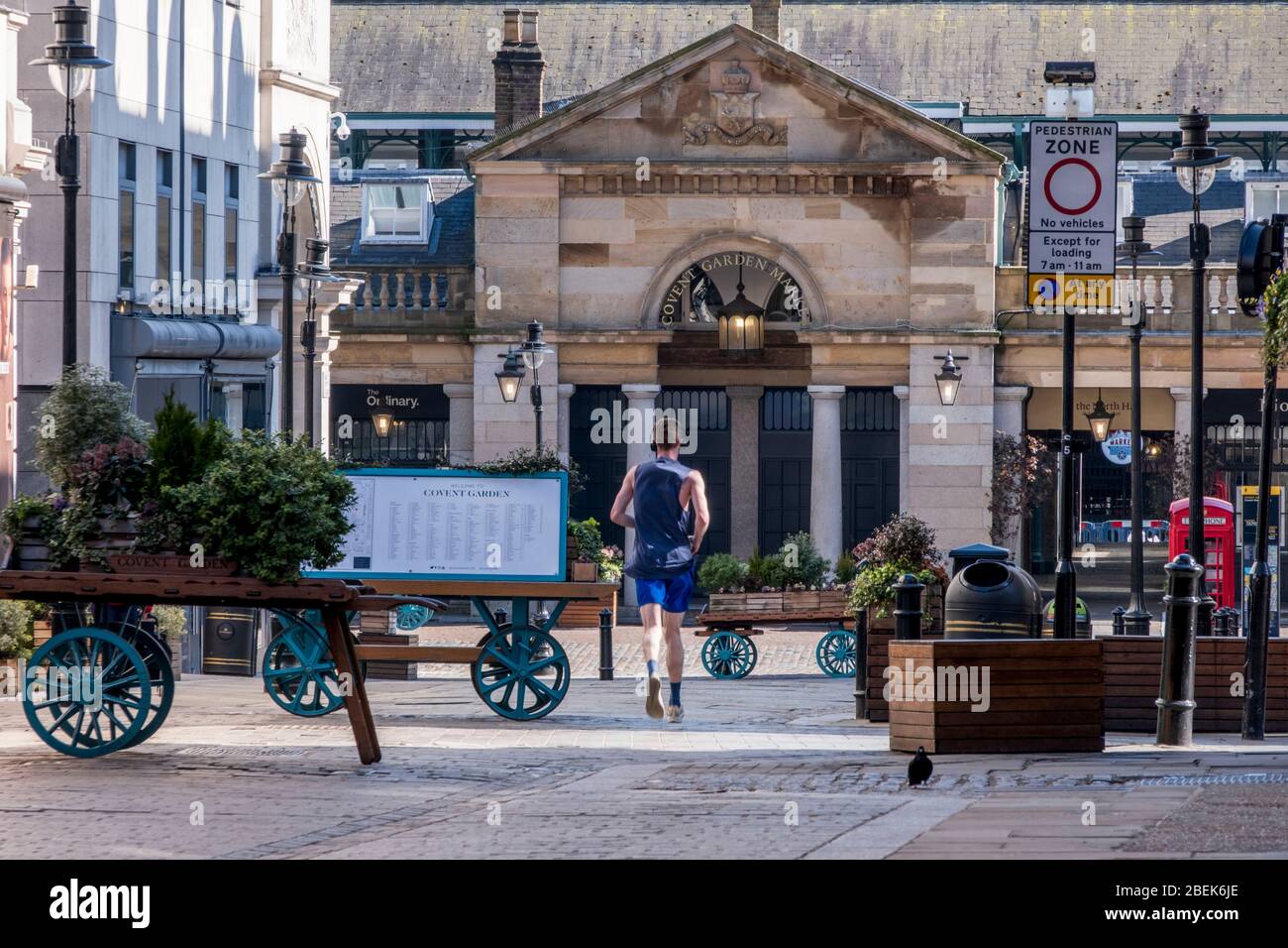 Regno Unito, Inghilterra, Londra. Un jogger che attraversa un Covent Garden vuoto, una delle aree di vendita più trafficate d'Europa, durante il blocco di Coronavirus Foto Stock