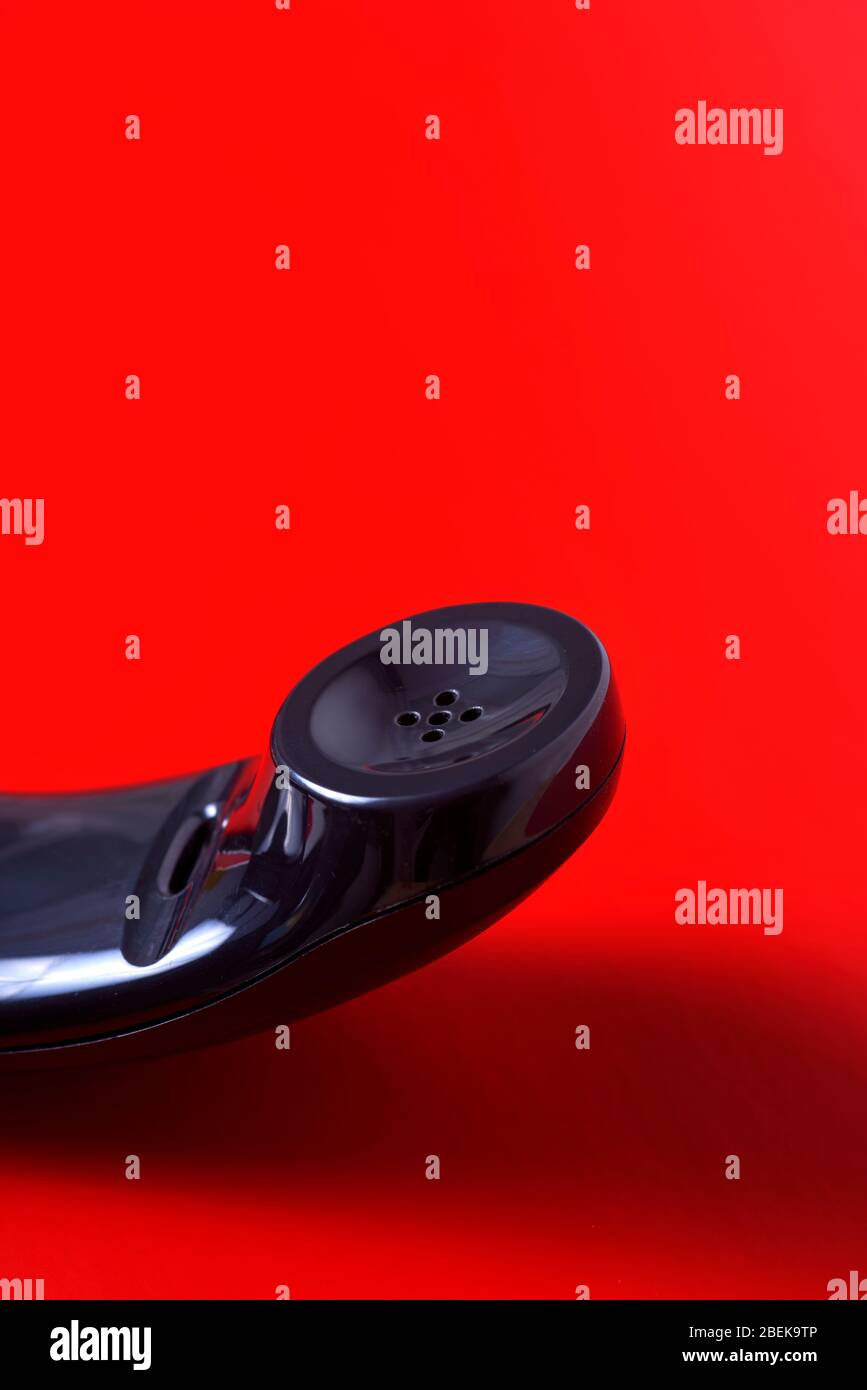 primo piano del ricevitore di un telefono nero su sfondo rosso con spazio vuoto sulla parte superiore Foto Stock