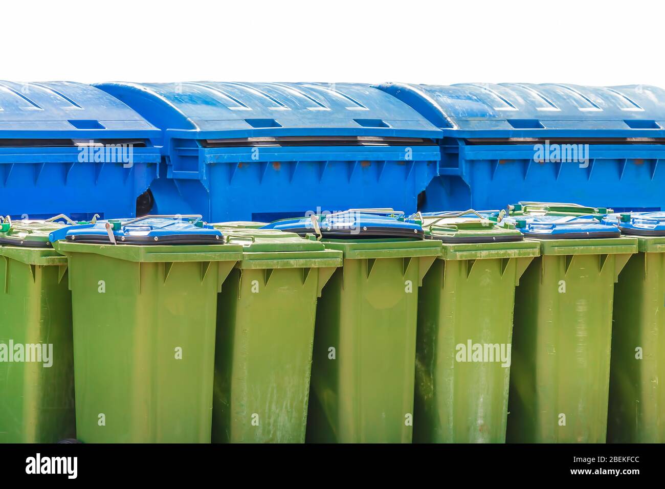 Grandi contenitori di rifiuti blu e piccoli contenitori verdi isolati su sfondo bianco Foto Stock